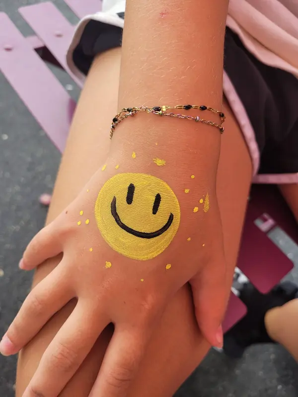 Smiley face painted on a hand