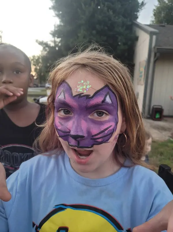 Child with a purple cat face paint design