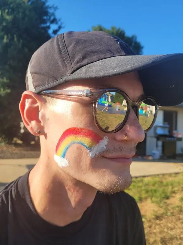 Man with a rainbow painted on his cheek