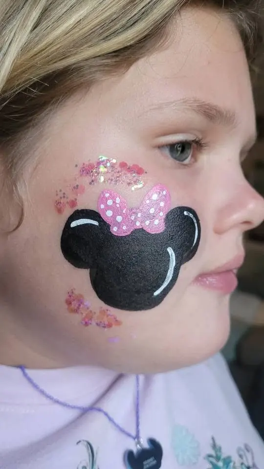 Mouse ears with a pink bow painted on a cheek
