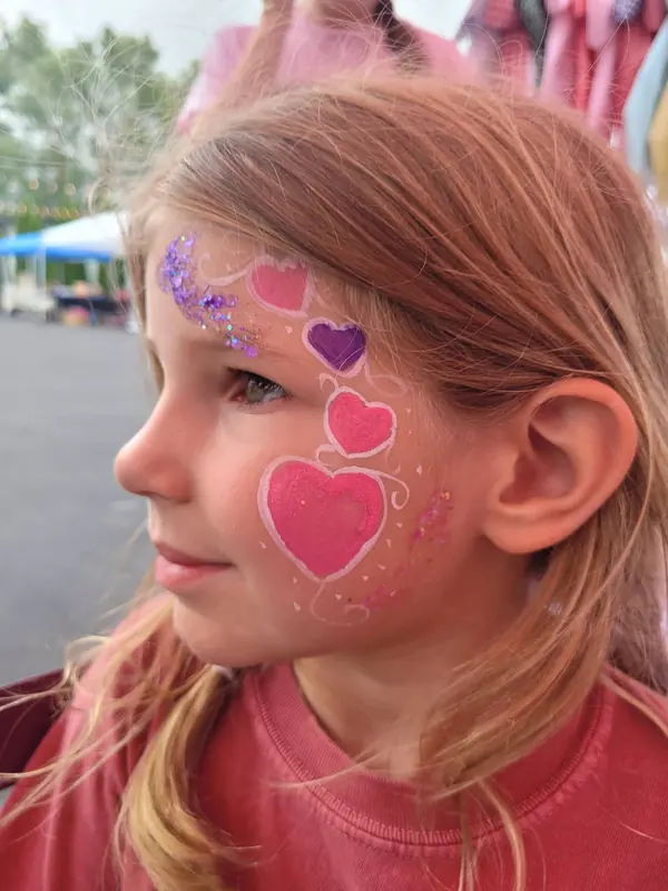 Girl with pink hearts painted down her cheek