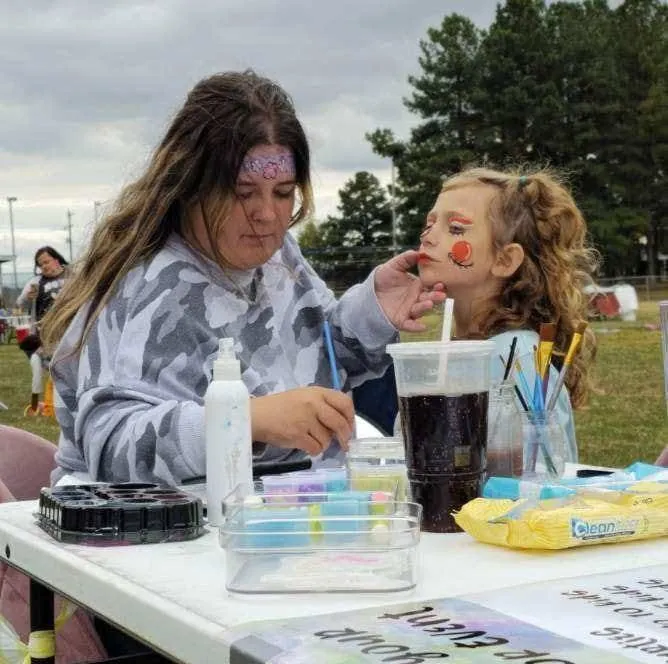 Jordan face painting a child at an outdoor event