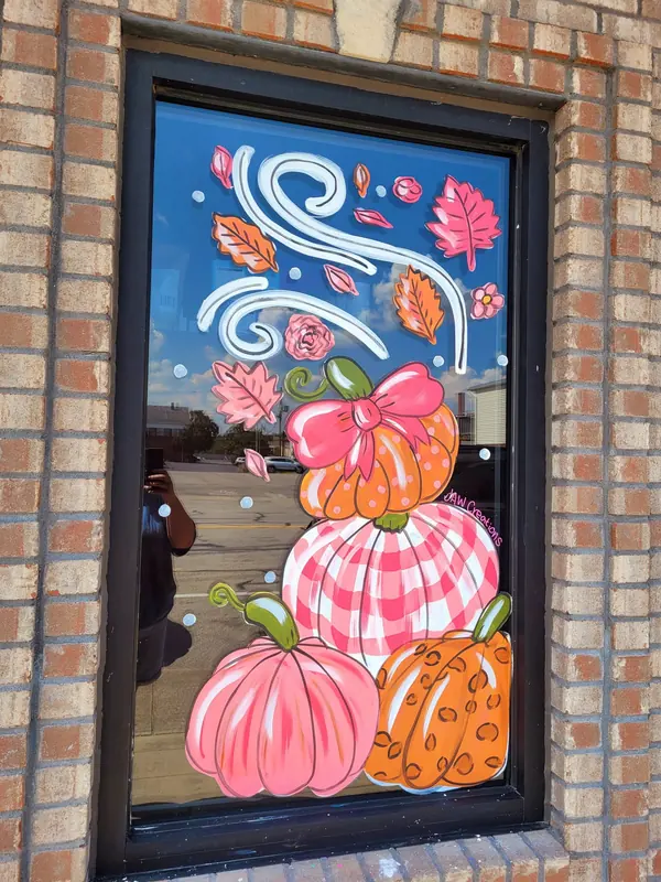 Window painted with stacked pink and gingham pumpkins