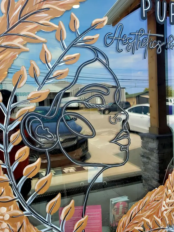 Window painted with a line-art face and golden leaves